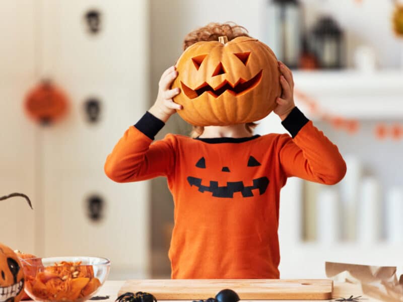 Enfant mettant une citrouille d'halloween devant sa tête